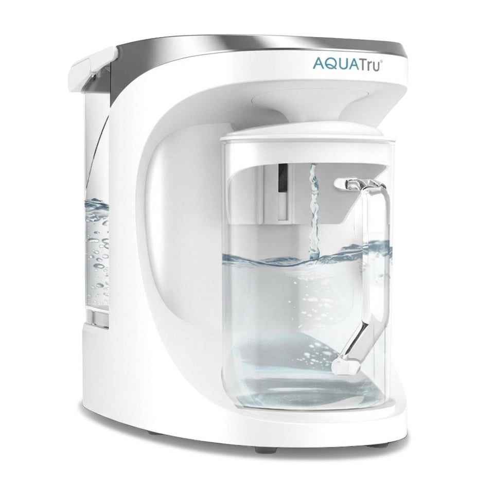 AquaTru glass carafe pours purified water for daily hydration.