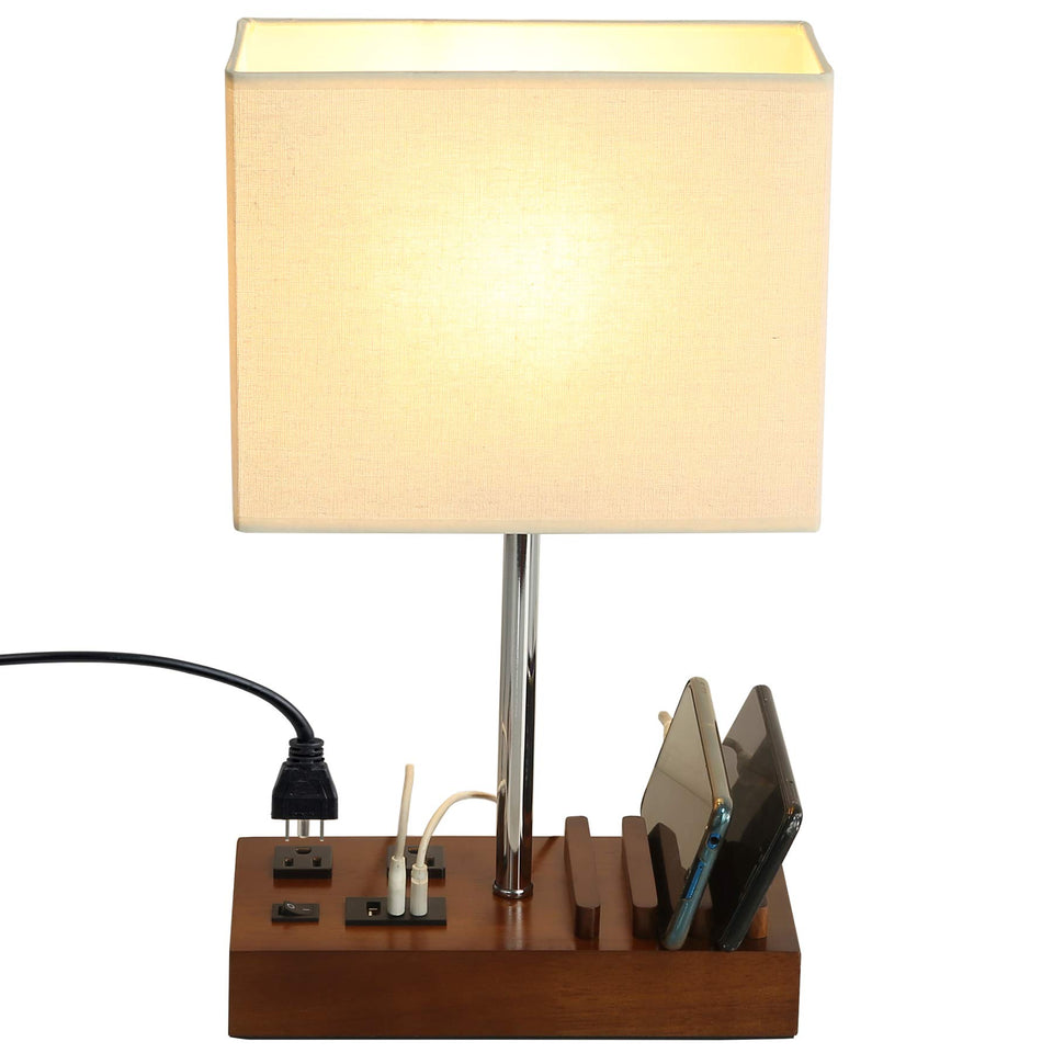 Briever USB table lamp with dual outlets and wooden base for organized charging.