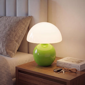 Dawnwake mushroom lamp with green glass shade lights a bedside area.