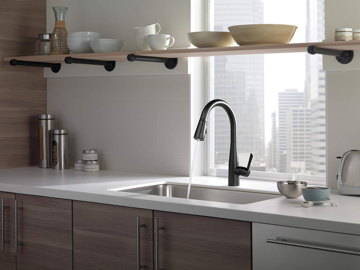 Delta Essa matte black faucet with pull-down sprayer in action for versatile cleaning