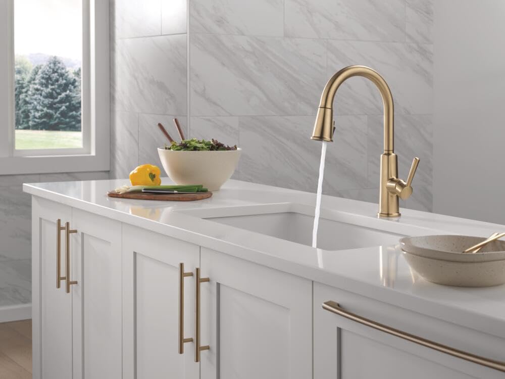 Champagne bronze Delta Finnridge faucet installed in a modern kitchen sink scene.
