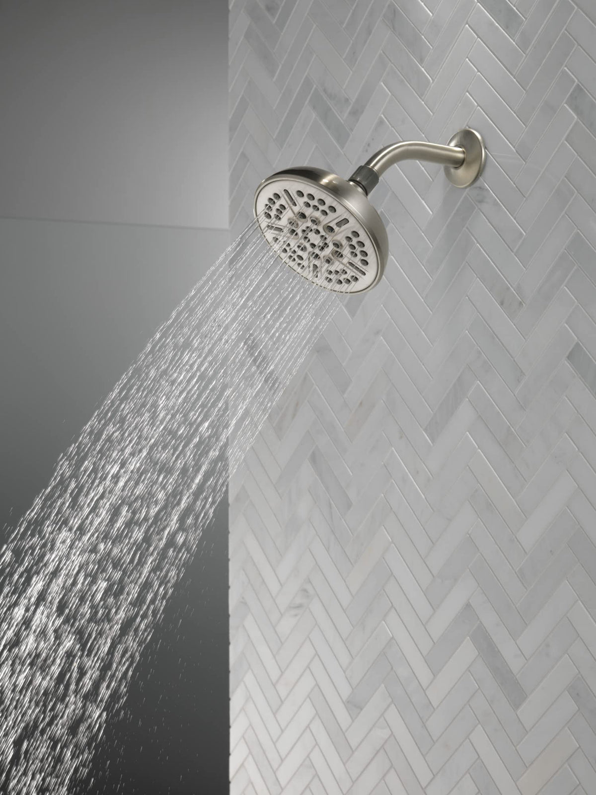 Delta brushed nickel shower head showing the full-body spray for even coverage.