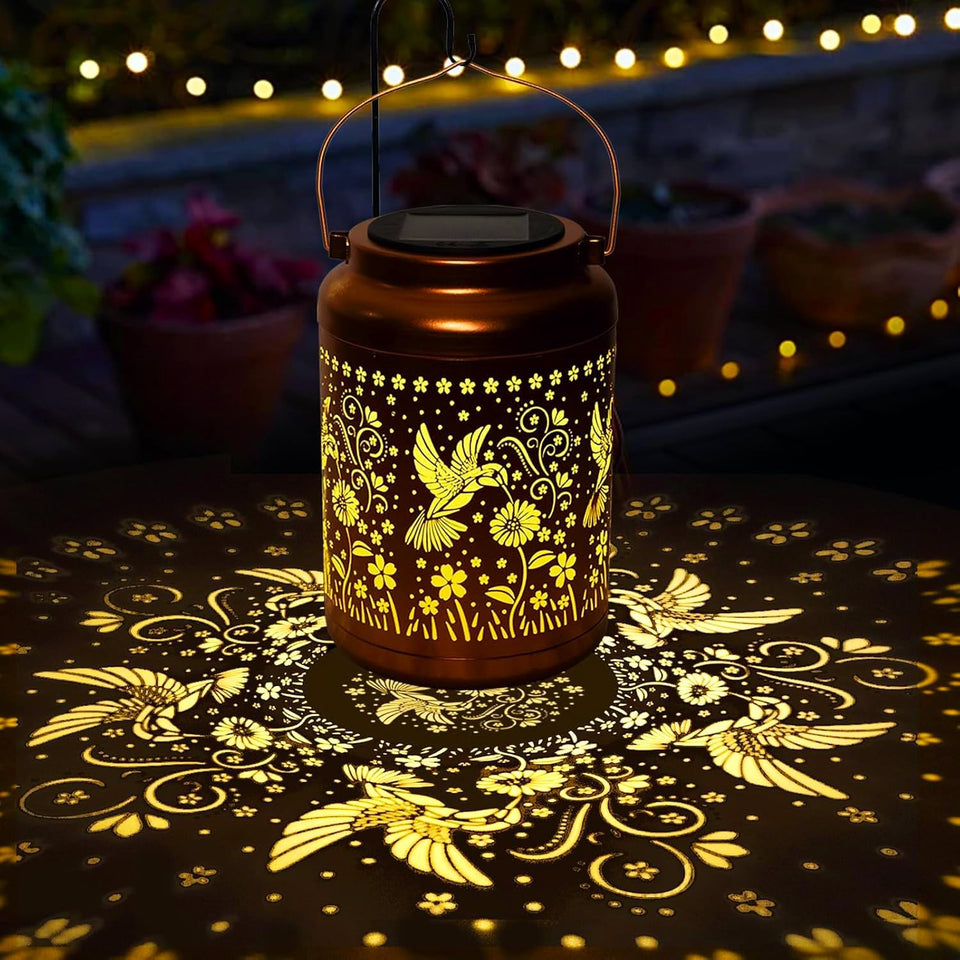 Dialan's hummingbird solar lantern glows along a garden path at dusk.