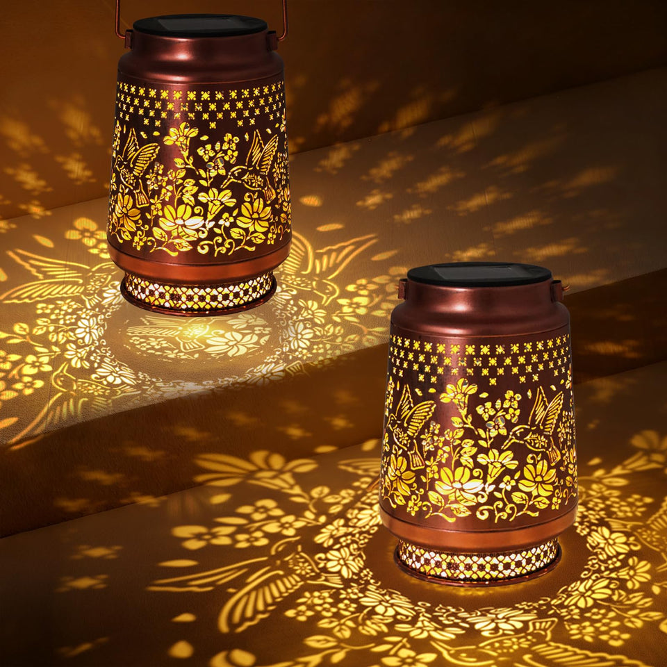 Fussion hummingbird solar lanterns glow softly in a garden setting