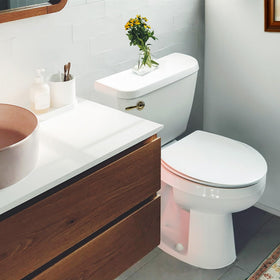 Korky 6021AM universal-fit mount demonstrated on a front-angle toilet tank.
