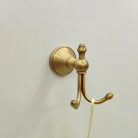 KWQKEM wall-mounted towel hook in vintage brass enhances bathroom decor and accessibility.