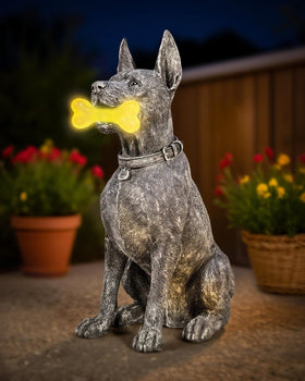 Miggley dog solar garden statue with glowing bone at night