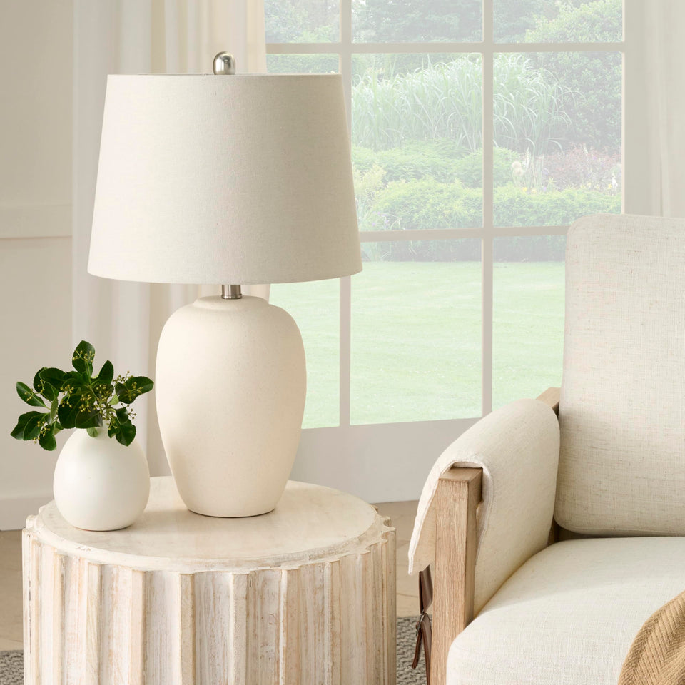 Nourison Home 23in ceramic jar lamp with urn silhouette adds warm ambient light for living spaces.