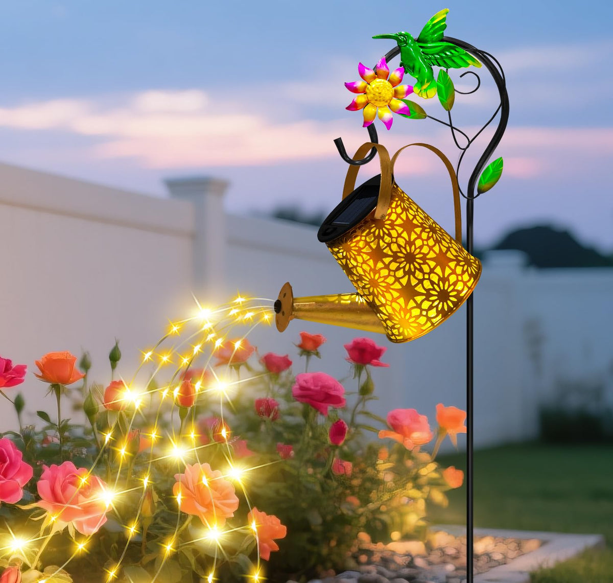 Ostritec solar watering can with hummingbird hook lights up garden at night.