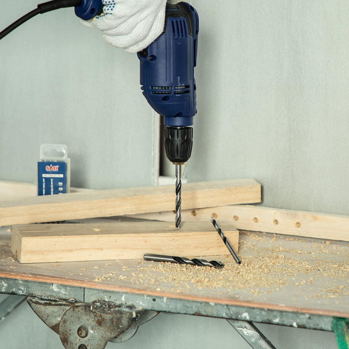 SALI assorted bit sizes laid out beside a plywood sheet for versatility.