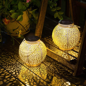 TAKE ME 2-pack white solar lanterns illuminate an outdoor garden scene.