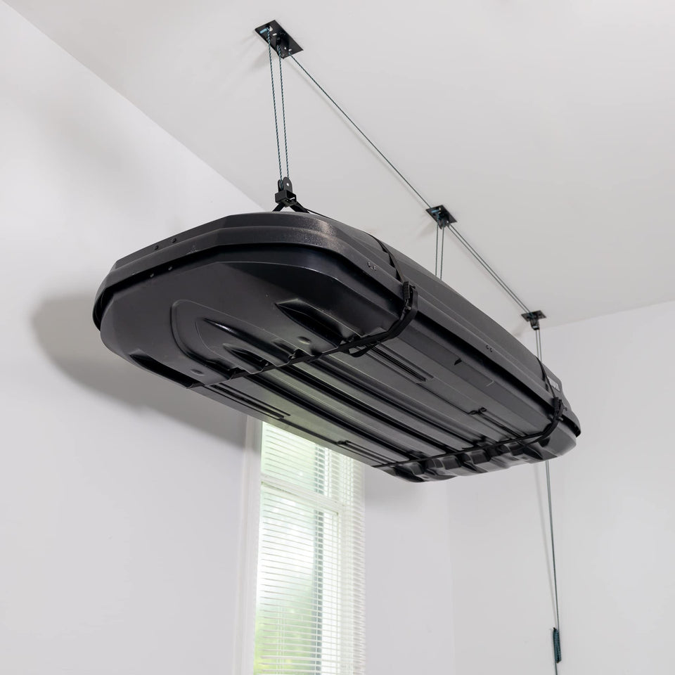 Teal Triangle ceiling storage hoist lifting a cargo box to free garage floor space.