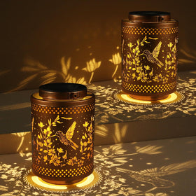 Tepaken hummingbird solar lantern outdoor metal glows warmly to create inviting garden ambiance.