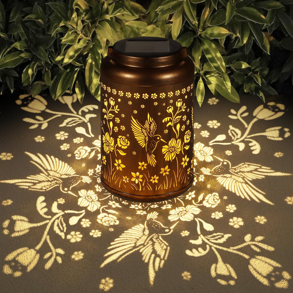 Tepaken solar lantern hummingbird design casts a warm garden glow at dusk