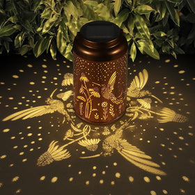 Tepaken solar lantern with hummingbird motif glows softly for garden ambiance.