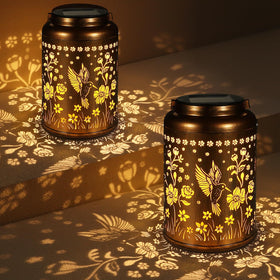 Tepaken solar lantern with hummingbird pattern lights an outdoor garden.