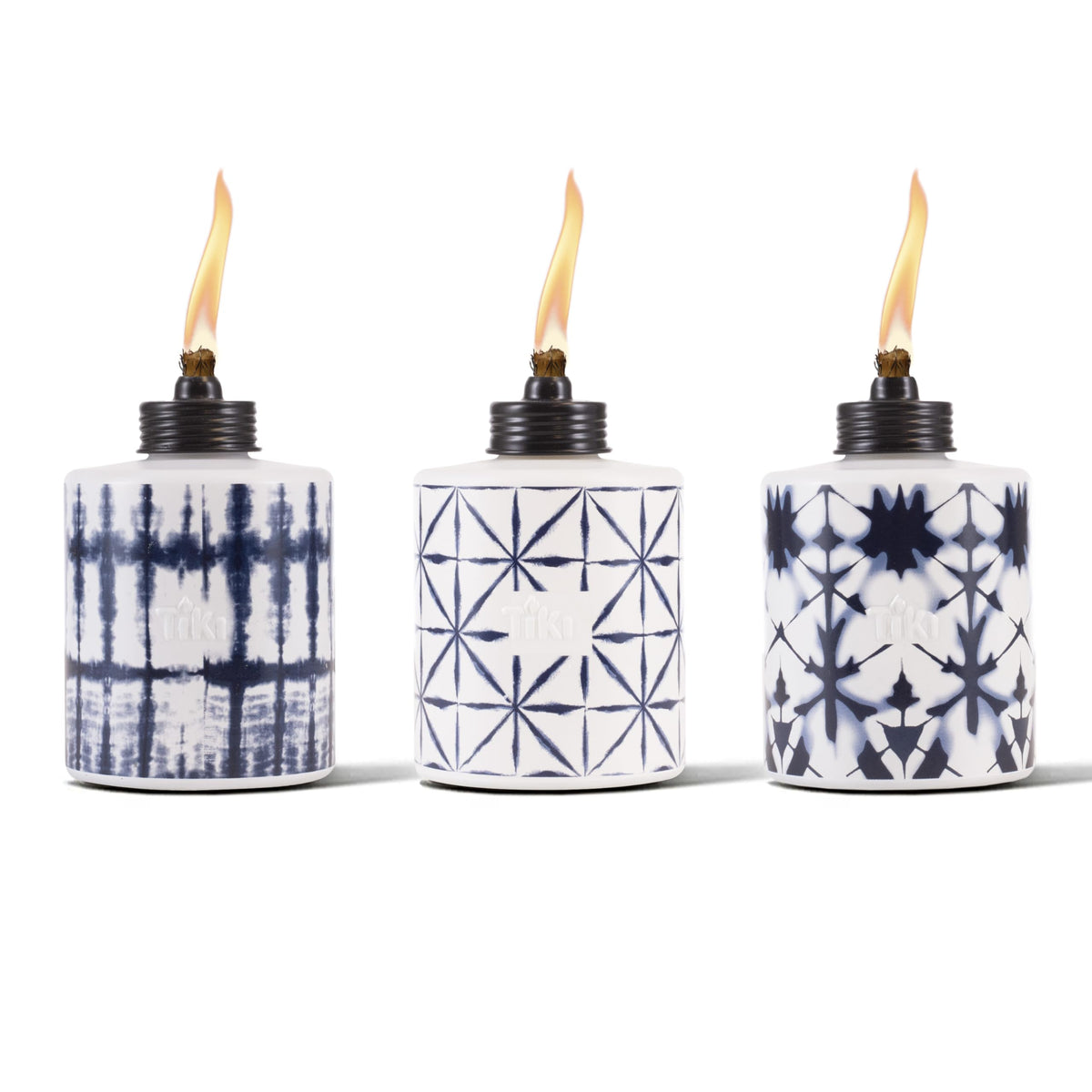 TIKI glass tie-dye tabletop torch on a dining table for warm outdoor ambiance.