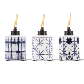 TIKI glass tie-dye tabletop torch on a dining table for warm outdoor ambiance.