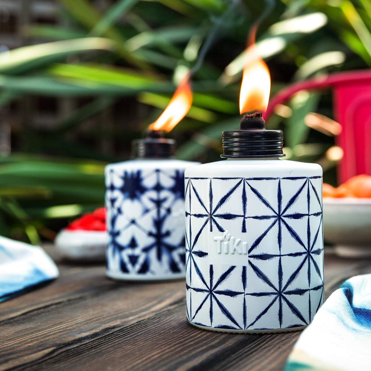Lit TIKI glass torch emits soft flame against twilight backdrop.