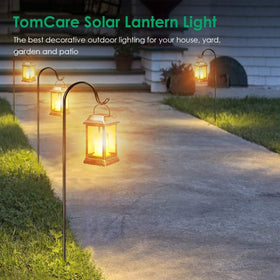 TomCare bronze lantern hanging from a shepherd's hook along a garden path.