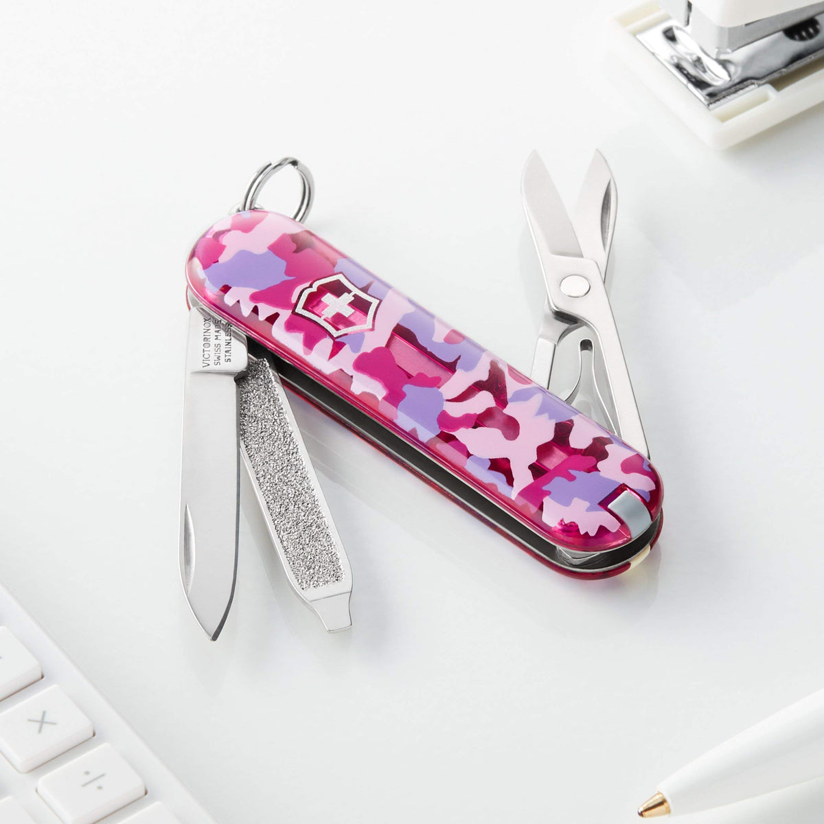 Victorinox Classic SD pink camouflage model in hand highlights compact durable Swiss design.