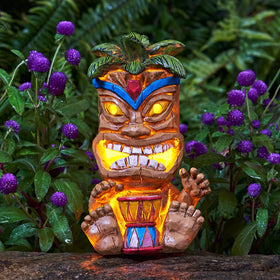 Yiosax solar tiki statue glows at dusk, enhancing garden ambiance.