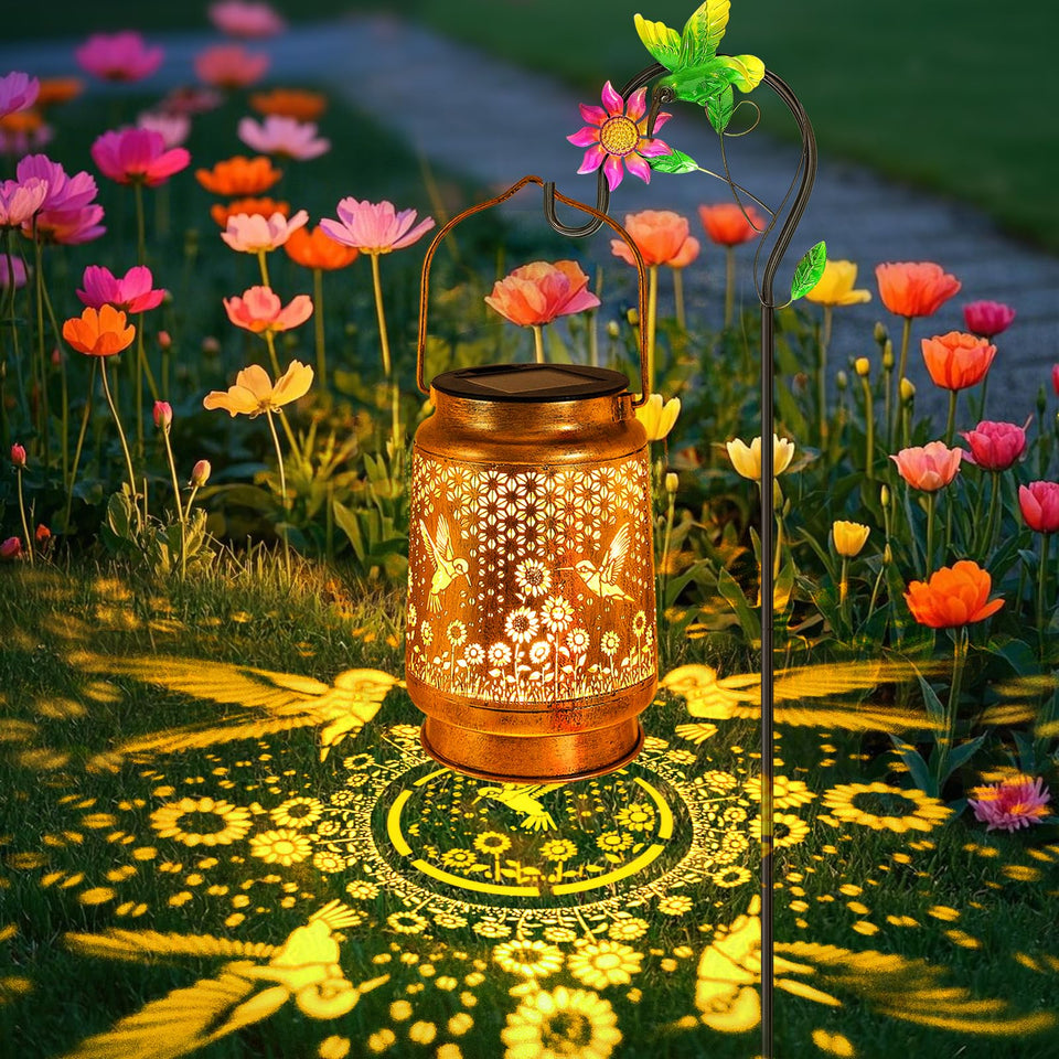YJFWAL hummingbird-sunflower-solar-lantern on shepherd hook creates warm garden ambiance after dusk.